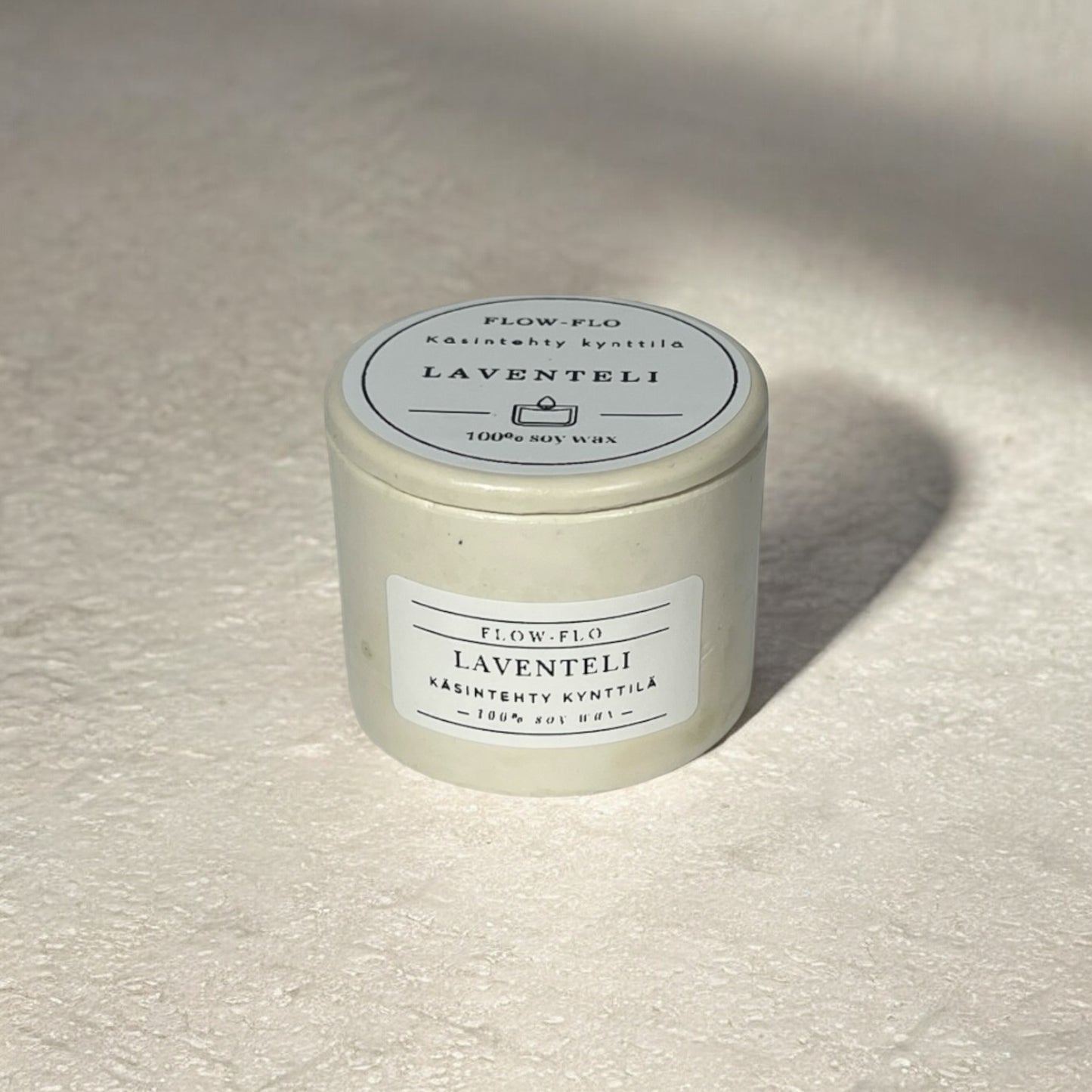 Flow Flo Laventeli kynttilä keraamisessa kipsipurkissa juuttinarulla, laventelinoksia taustalla – suomalainen käsintehty soijavahakynttilä