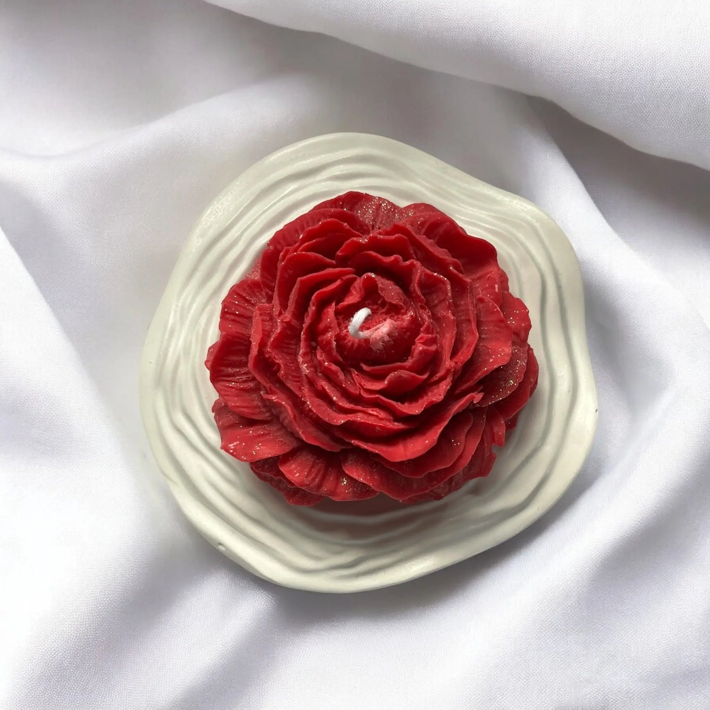 Artistic floral candle with a rich red hue.