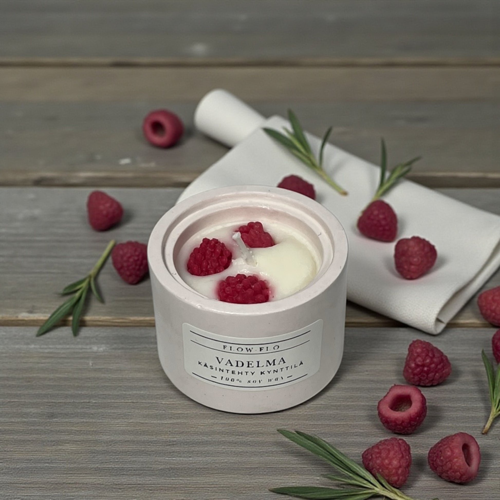 Flow Flo Vadelma kynttilä käsintehdyssä valkoisessa kipsipurkissa, vadelmia ja lehtiä taustalla – suomalainen käsintehty soijavahakynttilä