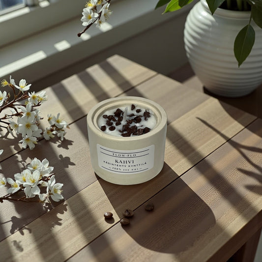 Flow Flo Kahvi kynttilä käsintehdyssä kipsipurkissa, kahvipapuja ja kukkia taustalla – suomalainen käsintehty soijavahakynttilä