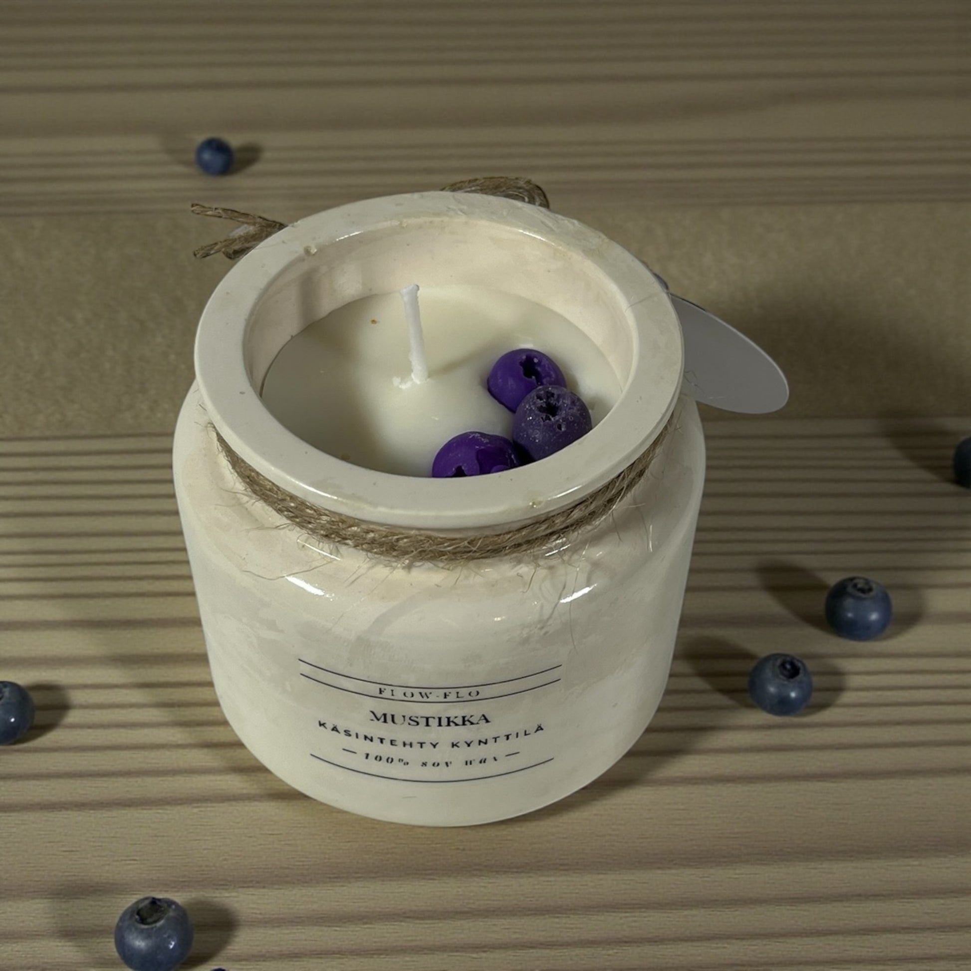 Käsintehty ekologinen tuoksukynttilä Mustikka Flow Flolta valkoisessa purkissa juuttinarulla koristeltuna – tuoreita mustikoita ja lehtiä vieressä, marjainen raikas soijavaha kynttilä kotiin.
