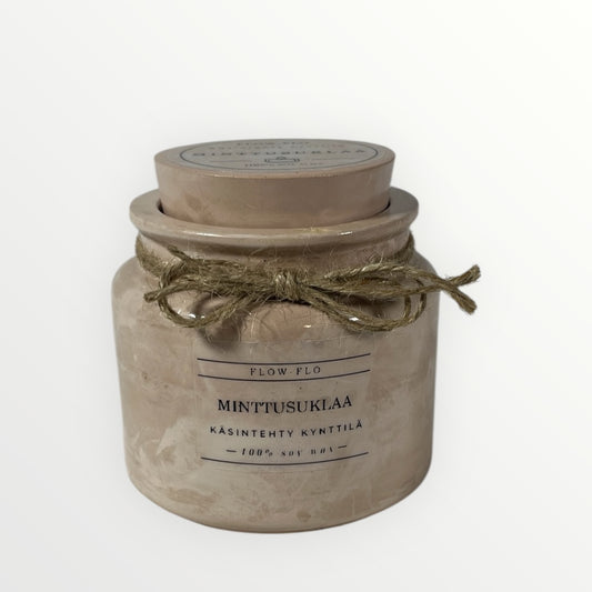 Flow Flo Minttusuklaa -käsintehty tuoksukynttilä vaaleanruskeassa rustiikkisessa purkissa juuttinarukoristeella, mintunlehtiä ja tummaa suklaata ympärillä – raikas ja makea ekologinen soijavaha kynttilä sisustukseen