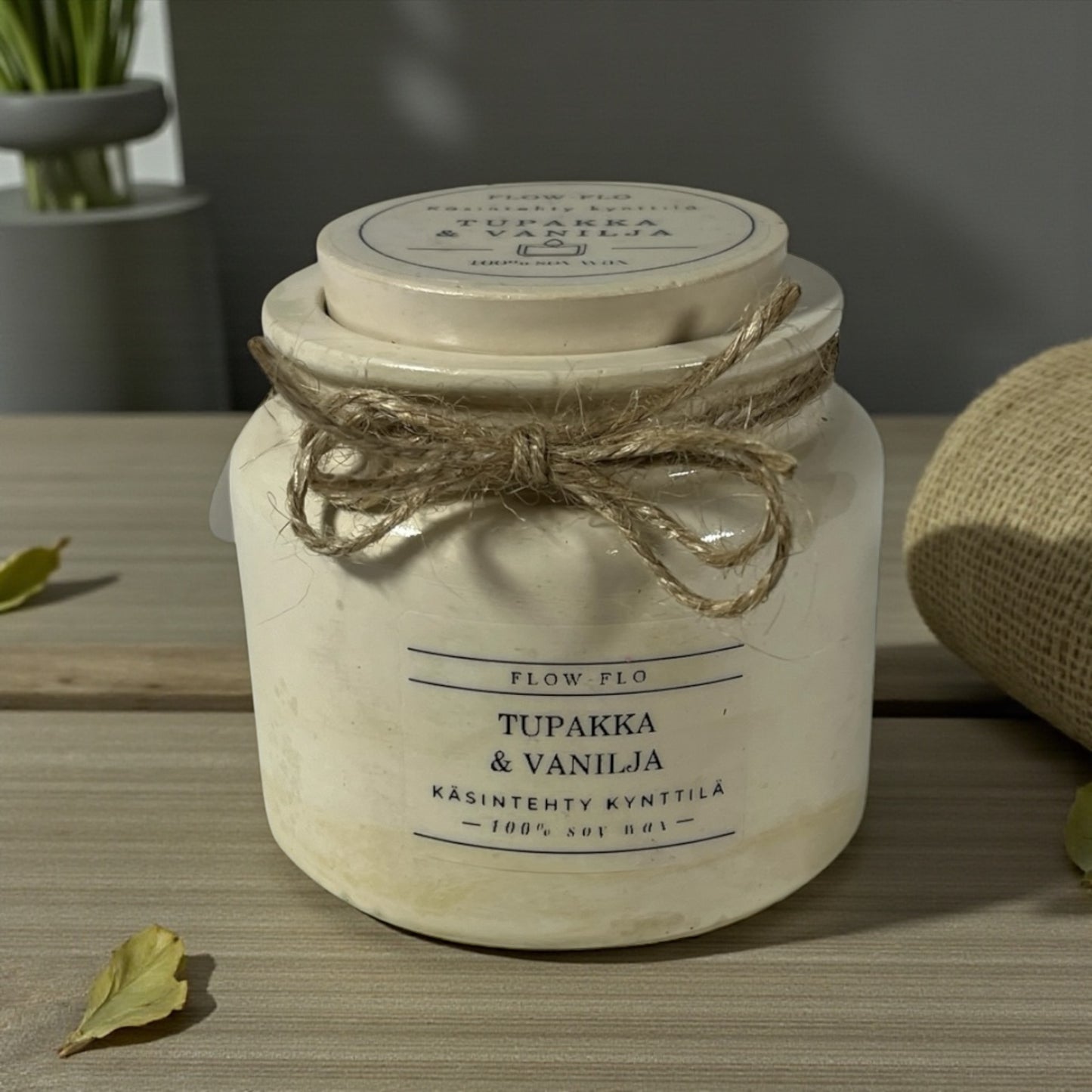 Flow Flo Tabak & Vanilja käsintehty tuoksukynttilä vaaleanbeigessä rustiikkisessa purkissa juuttinarukoristeella puupöydällä – lämmin savuisen tabakin ja makean vaniljan ekologinen soijavaha kynttilä sisustukseen.