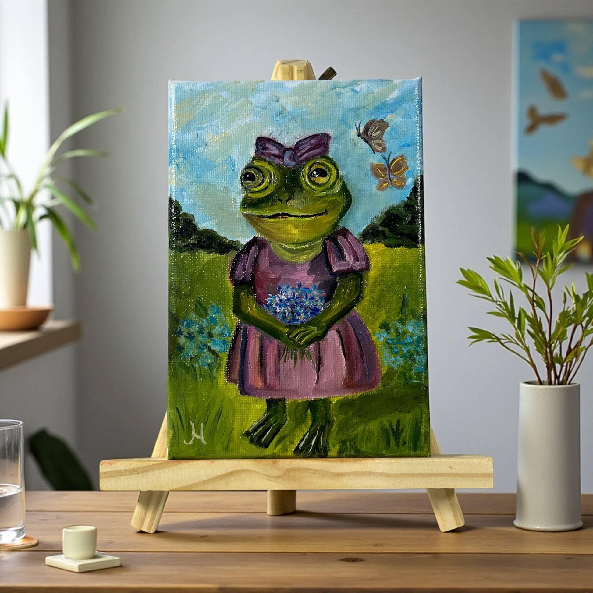 Käsintehty sammakkotaulu kukkien ja perhosten keskellä