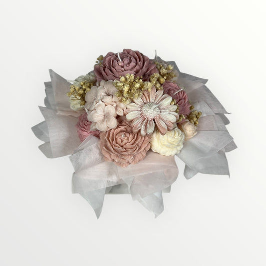 Pastellisävyinen kynttiläkukkakimppu, jossa vaaleanpunaisia ja beigejä kukkia sekä kuivattua kipsikukkaa valkoisessa silkkipaperissa.