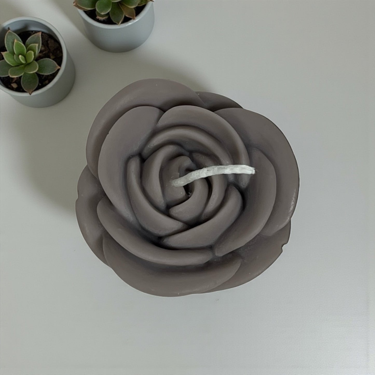 Decorative rose-shaped wax candle with realistic petal design.