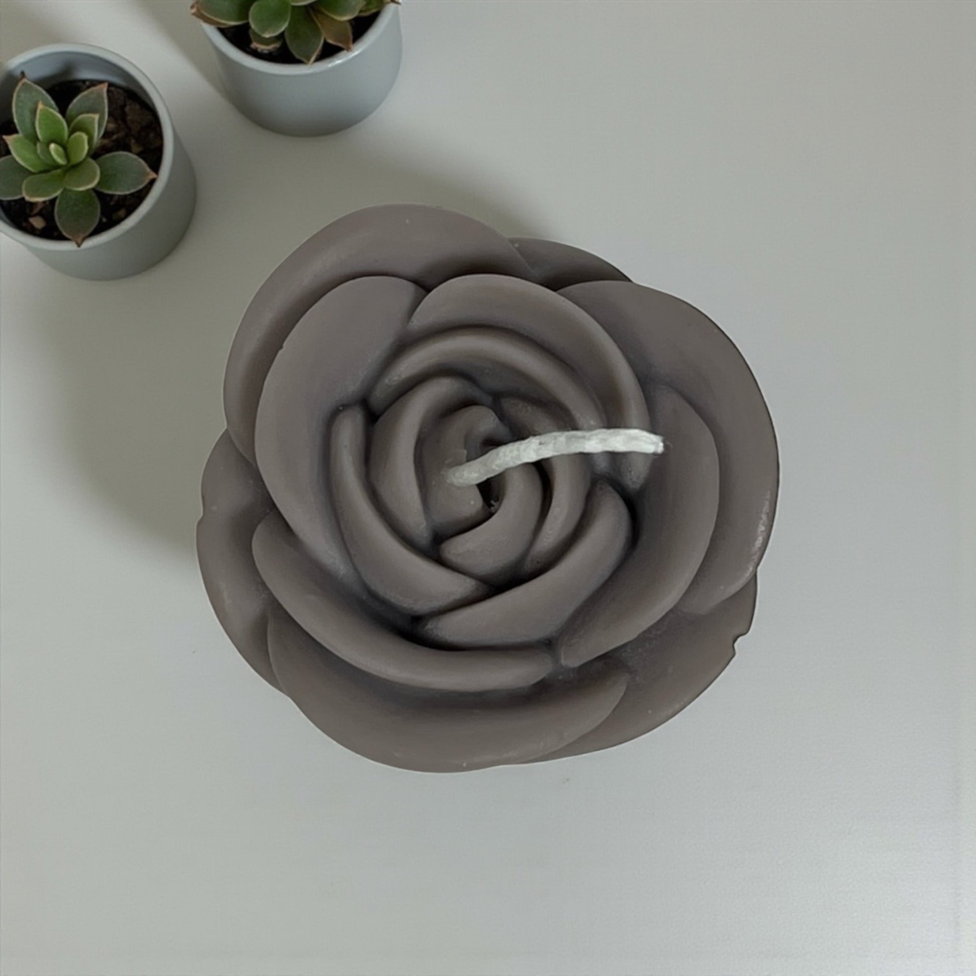 Decorative rose-shaped wax candle with realistic petal design.