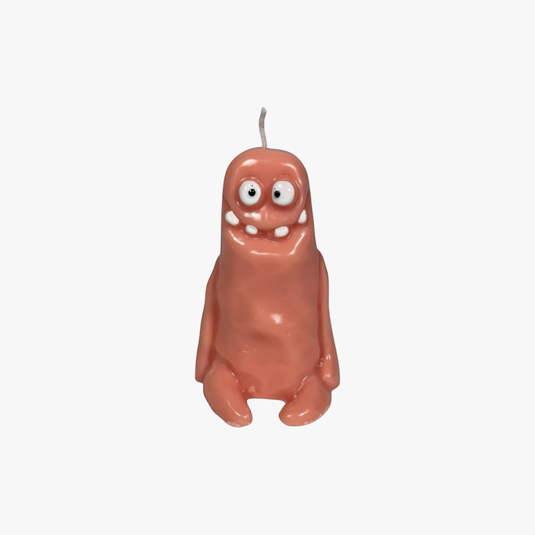 Flow-Flo handmade salmon pink soy wax "Cute Monster" candle with white teeth and googly eyes.